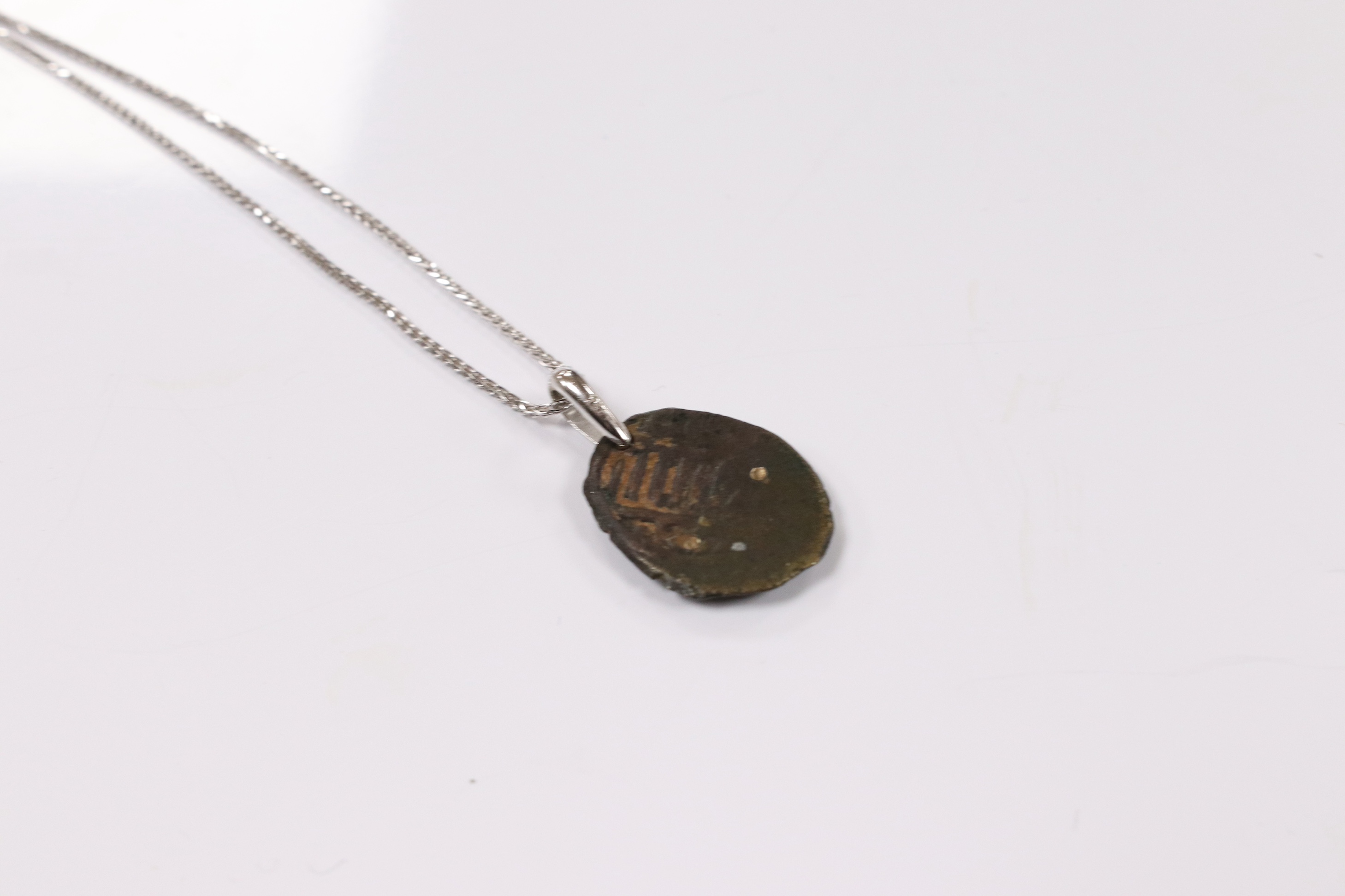 A modern 18k white metal mounted pendant, modelled as an ancient coin later mounted with brilliants, overall 25mm, on an Italian 18k white metal fine link chain, 44cm, gross weight 6 grams. Condition - poor to fair